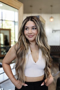 a woman with long wavy hair standing in front of a hair salon