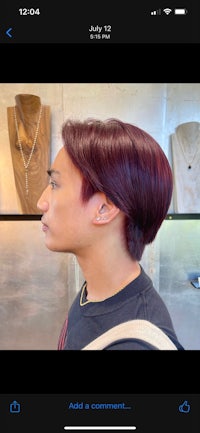 a man with a burgundy colored hair in front of a mirror