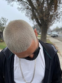 a man wearing a white jacket and a chain necklace