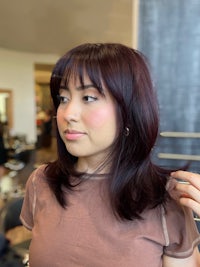 a woman in a brown t-shirt is looking at her hair