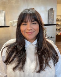 a woman with long brown hair smiling in a salon