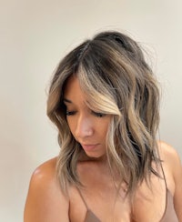 a woman wearing a tan tank top and a wavy bob